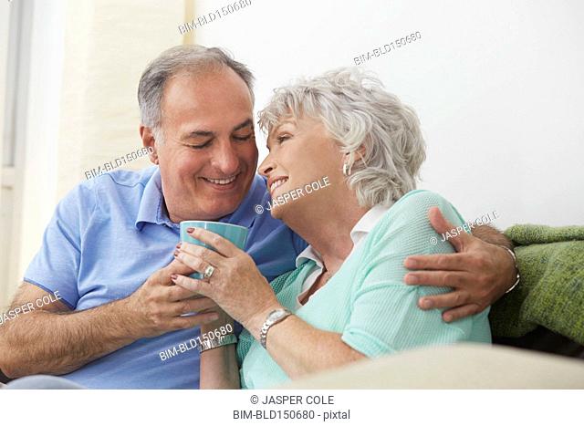 Older couple drinking coffee on sofa
