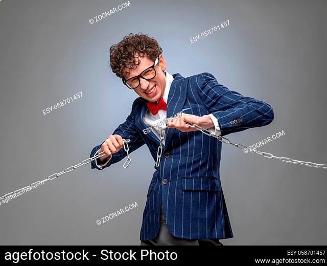 Funny businessman breaking the chain by hands for liberation as a symbol of work captivity