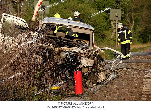 23 April 2019, Lower Saxony, Filsum: Firefighters secure an accident site at a level crossing. A 47-year-old collided with a train with his car at a level...