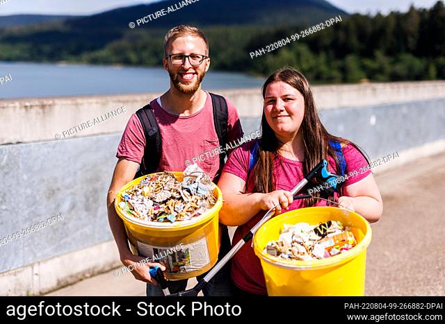 PRODUCTION - 06 July 2022, Baden-Wuerttemberg, Forbach: René Engels and his girlfriend Michaela stand on the Schwarzenbachtalsperre and hold grapple tongs as...