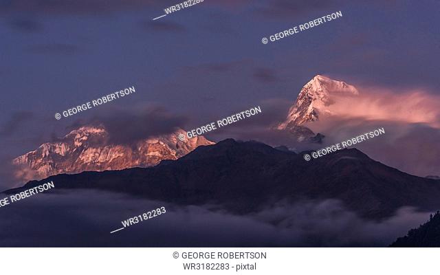 The clouds gradually clearing to reveal the evening light on Annapurna South, viewed from Poon Hill, Himalayas, Nepal, Asia