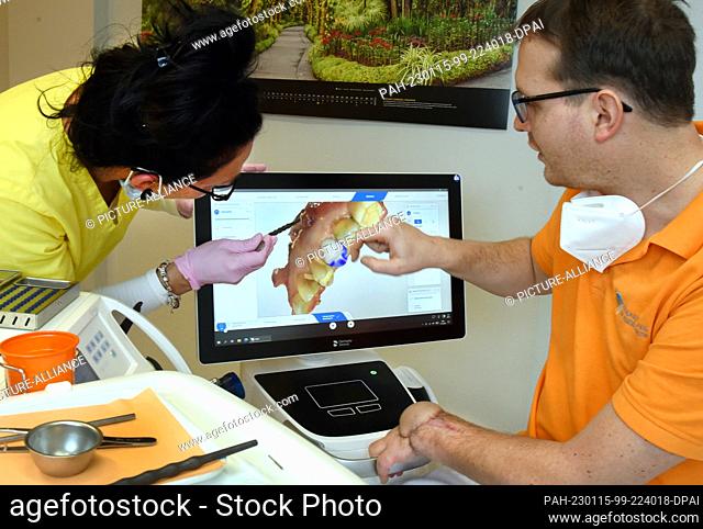 11 January 2023, Leipzig: In his dental practice, dentist Andreas Huth discusses the use of a Zeno crown on a patient with his dental assistant Nancy on the...