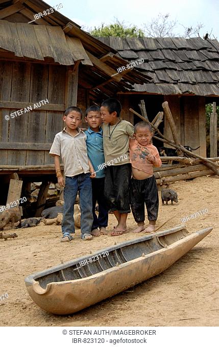 Everyday life in poverty for the Hmong minority, children standing behind the shell of an american bomb from the Vietnam war used as a cattle watering tank