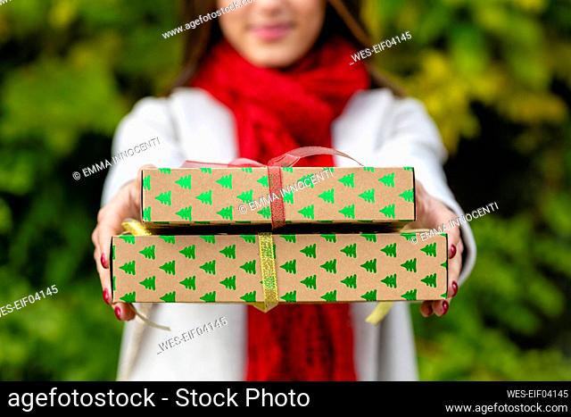 Young woman in warm clothing giving Christmas presents