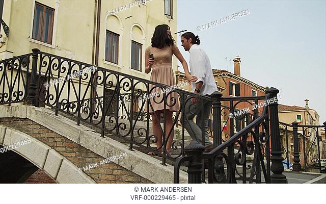 MS TU Couple walking up arch bridge and taking photos of canal / Venice, Veneto, Italy