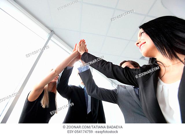 Happy smiling business people giving high five in the office