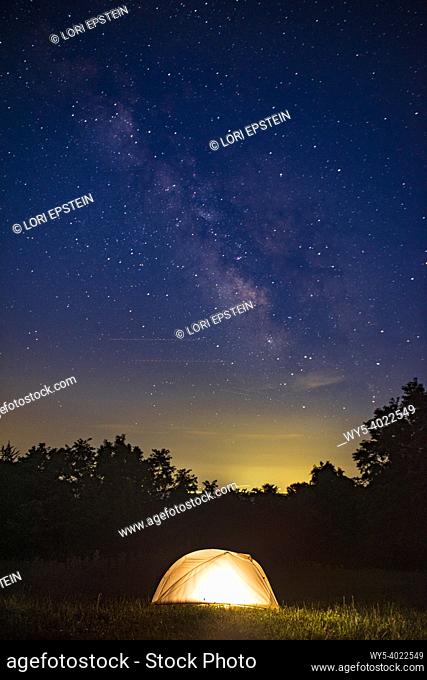 The Milky Way rises in the sky above an illuminated tent