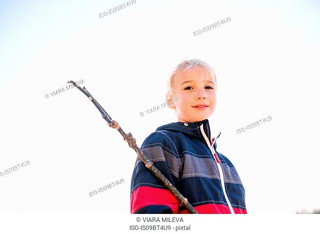 Boy with stick against clear white sky
