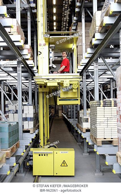 An employee of the Weltbild Publishing Group in the logistics centre taking a selection of books in a selective distribution warehouse with a shelf control...