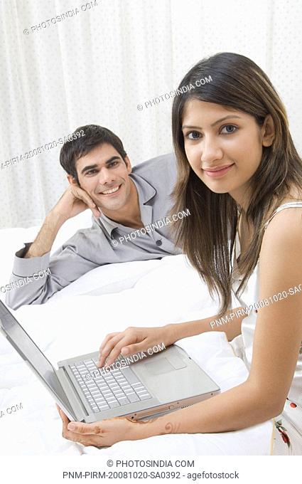 Woman working on a laptop and a man reclining beside her