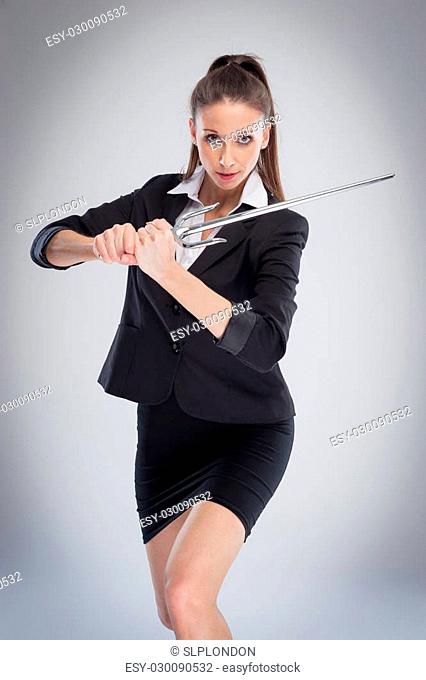 Sexy woman exercise training with a steel sword. Studio shot on grey background