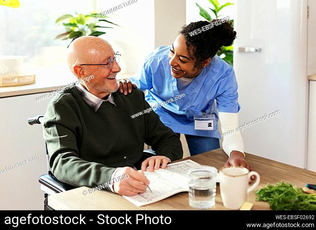 Happy caretaker assisting senior man at home
