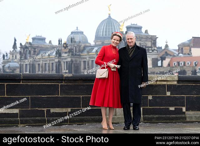 07 December 2023, Saxony, Dresden: Queen Mathilde and King Philippe of Belgium stand on the Augustus Bridge in front of the dome of the Kunstakedemie