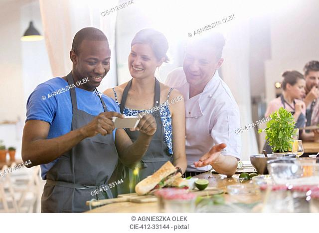 Man photographing food in cooking class kitchen