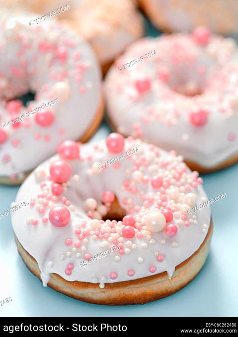 Delicious tender donuts glazed white glaze and sprinkled with pink pearl dressing. Idea decorating donuts for wedding, romantic event, celebration
