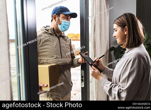 deliveryman in mask and woman signing digital form