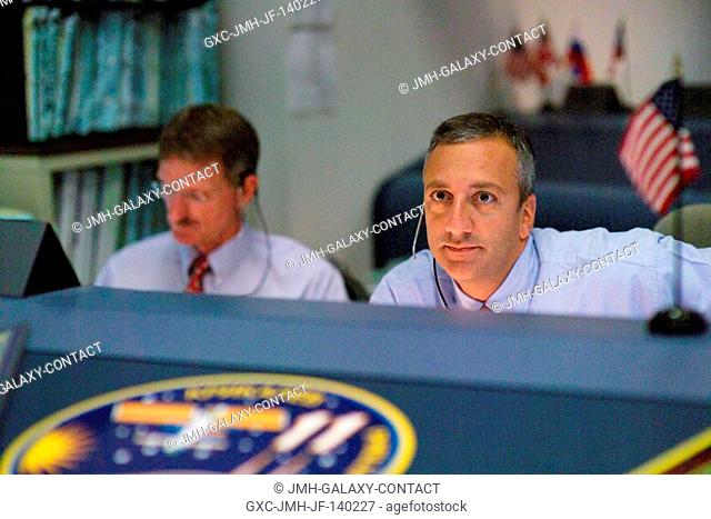 Astronaut Michael J. Massimino (right), spacecraft communicator (CAPCOM), watches today?s extravehicular activities (EVA) on the large screens from his console...
