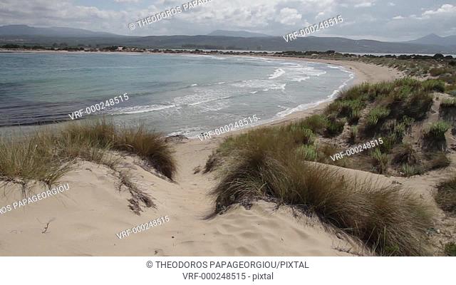 A woman walking on the sand dunes of Voidokilia beach. Messenia, Peloponnese, Greece