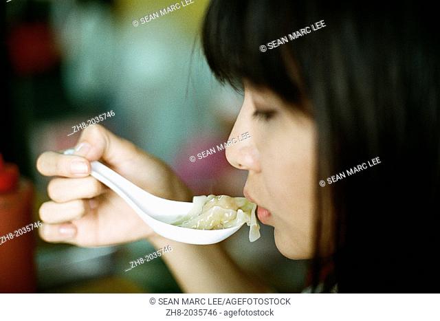 A woman about to eat a won ton soup dumpling in Kaohsiung, Taiwan