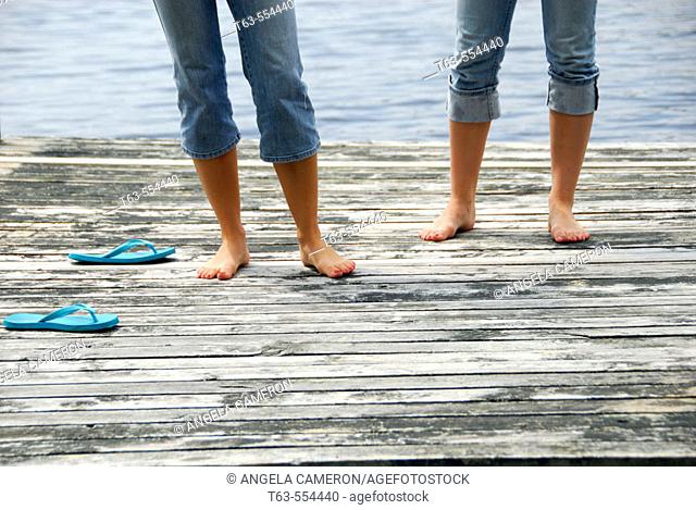 legs of girl 13 girl 18 standing on dock together