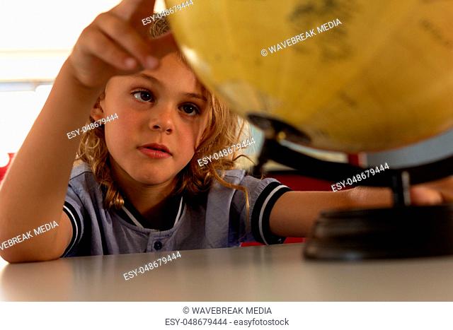 Schoolgirl studying globe at desk in a classroom