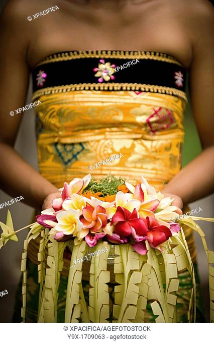 A close-up of Balinese woman holding a floral arrangement