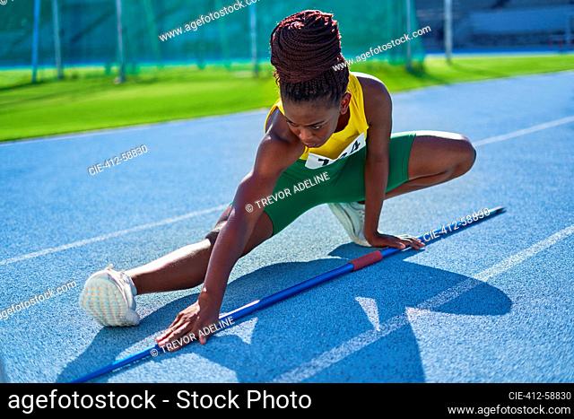 Atleta de pista y campo femenino con estiramiento de jabalina en pista soleada