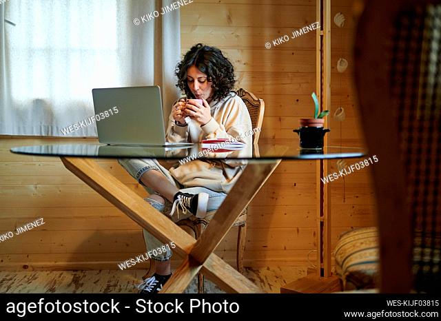 Mid adult woman drinking tea at table in living room