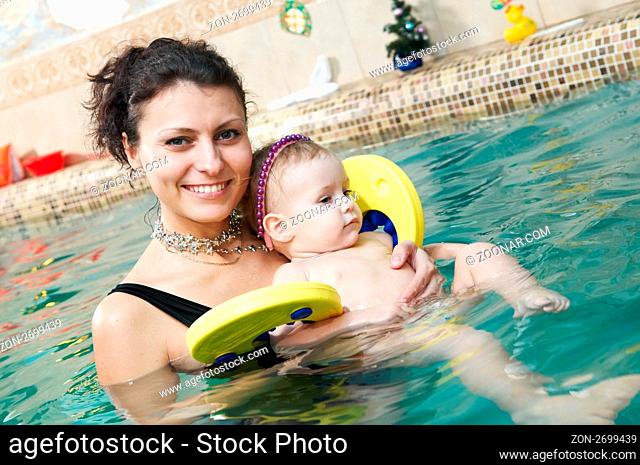 happy smiling little girl with mother swimming at water pool