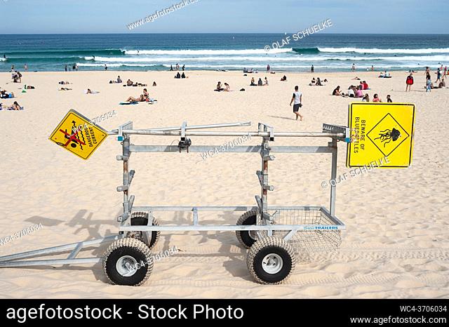 Sydney, New South Wales, Australia - A trailer with warning signs is parked in the sand as people sunbathe and enjoy themselves on famous Bondi Beach