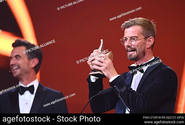 17 September 2021, Saxony, Leipzig: German presenter Joko Winterscheidt (r) receives the ""Goldene Henne"" award from presenter Florian Silbereisen for the...
