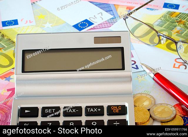Taschenrechner, Brille und Kugelschreiber auf Euroscheinen