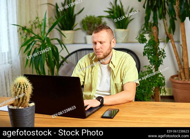 Man typing something on laptop, working on computer at home or office, business man entrepreneur using computer looking at screen working in internet sit at...