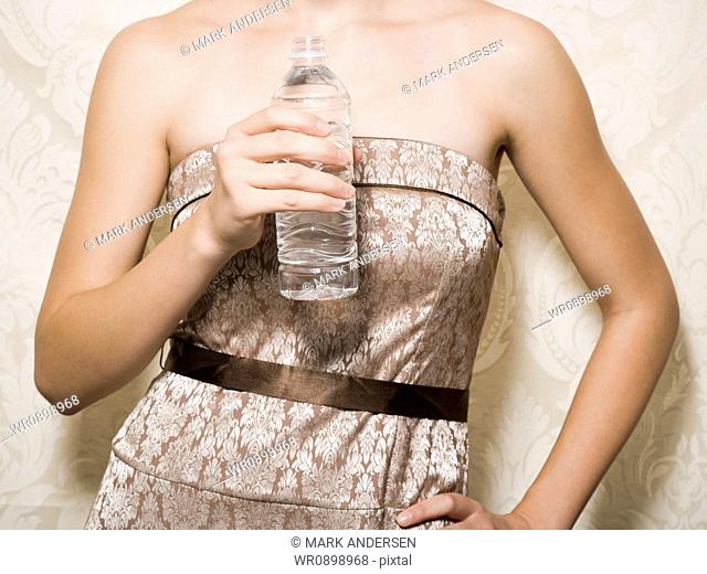 Mid section view of woman in dress holding bottled water