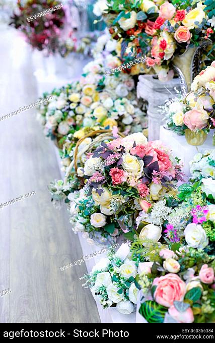 Bouquet artificial roses with leaves, interior design smooth rows of bouquets in a flower shop, decoration artificial flower pink green white lilac rose bouquet