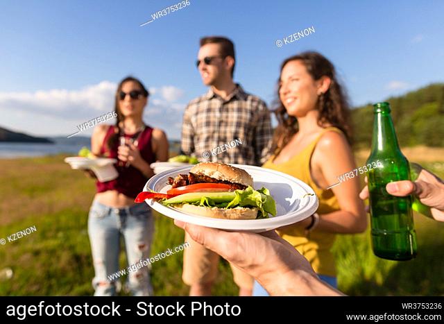 Group of friends with typical menu of summer barbecue party, burger and beer
