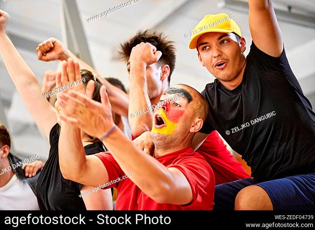 Friends cheering together at sports event in stadium