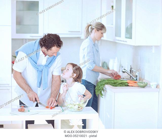 Father and Daughter looking at each other whilst preparing healthy meal in kitchen