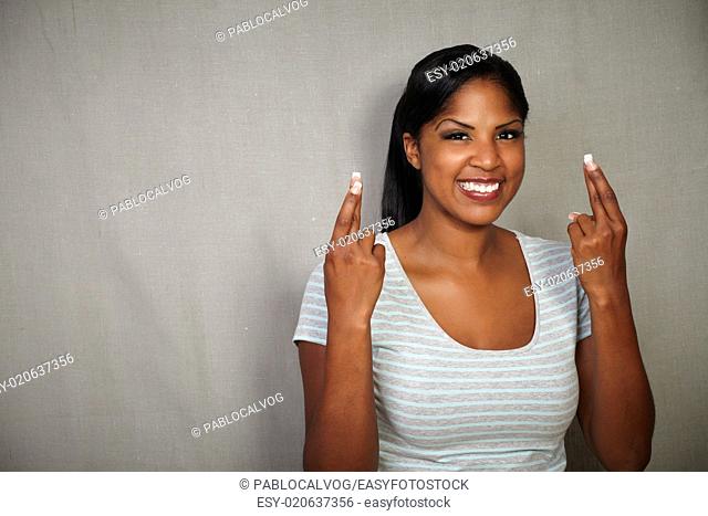 Young female of afro-american ethnicity wishing with fingers crossed - copy space