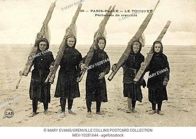 Shrimp fishing at Le Touquet, France. Five teenage girls carrying rolled-up fishing nets, designed to catch shrimp