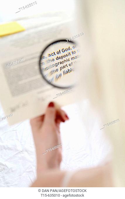 Woman reads a contract fine prints using a magnifier says act of God and deposit