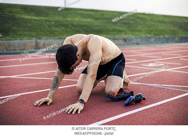 Athlete kneeling on a tartan track after finishing a race