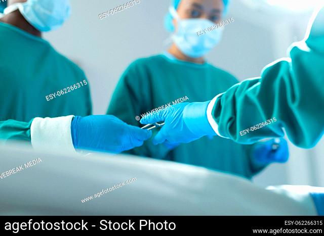Low angle of surgeons passing surgical tools in operating theatre during operation, with copy space