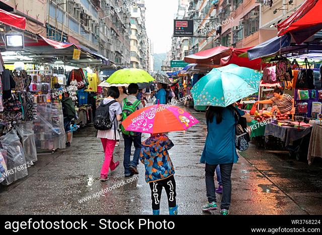 Kowloon, Hong Kong - April 23, 2017: People With Umbrellas at Street Market Rainy Day in Kowloon, Hong Kong
