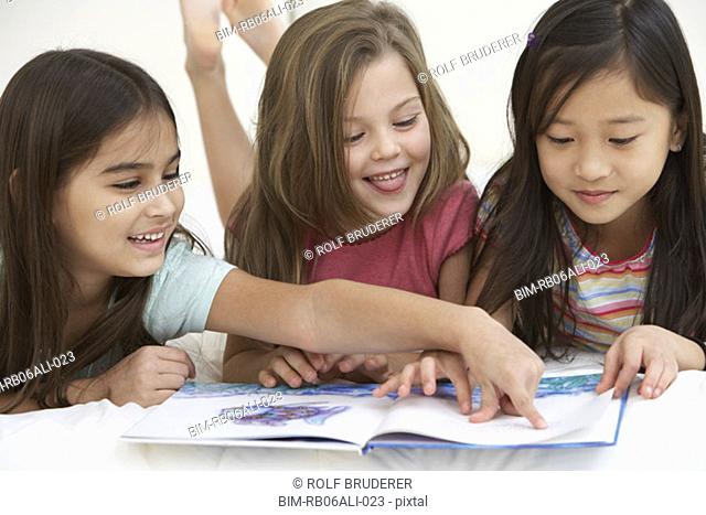 Three young girls reading book