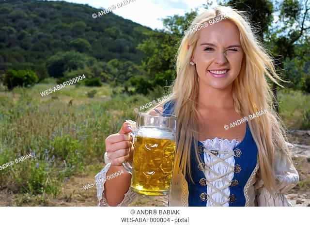 USA, Texas, Young woman with traditional clothing holding beer mug, smiling, portrait