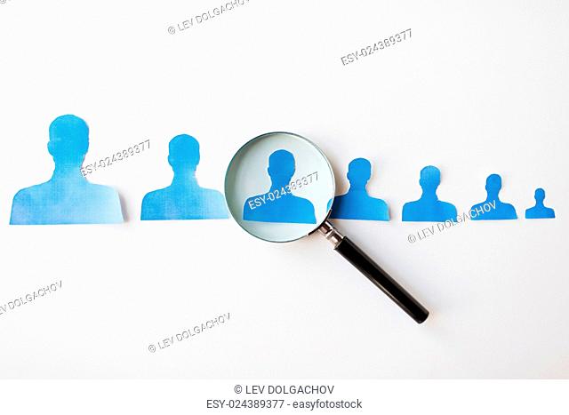 business, employment, population, career and hiring concept - close up of paper people shapes and magnifying glass on white board