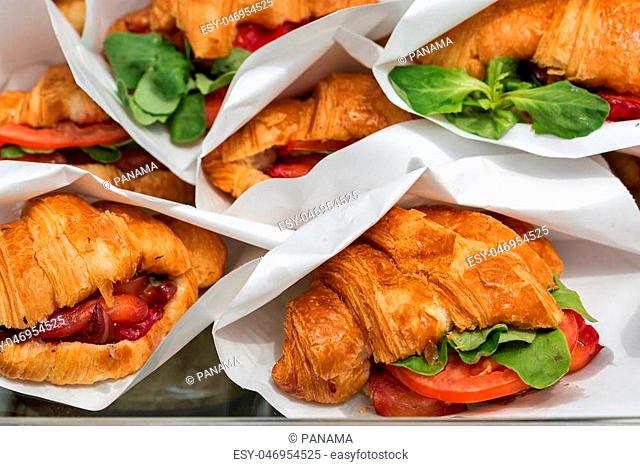 Street food croissants with salmon served in paper bags closeup