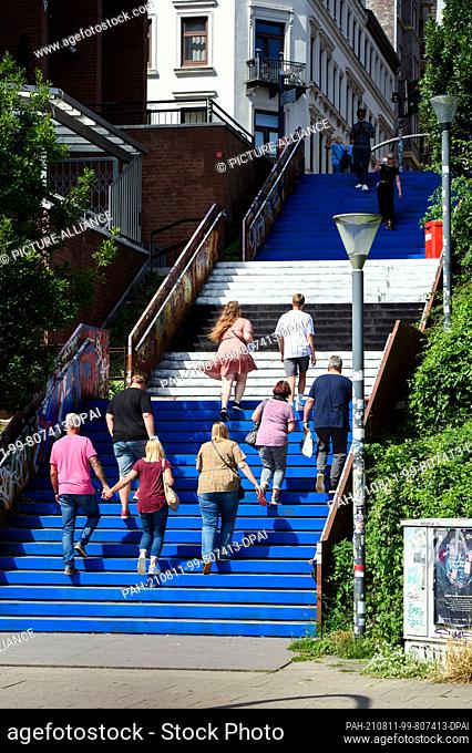 11 August 2021, Hamburg: Hamburgers and tourists walk up and down the St. David's Stairs in the St. Pauli district, painted in the HSV colors of blue