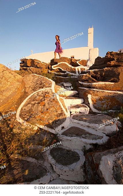 Woman standing in front of a chapel at the top of the hill in Chora, Ios, Cyclades Islands, Greek Islands, Greece, Europe